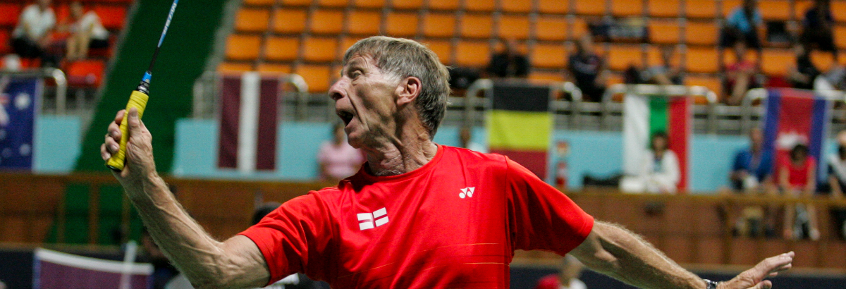 Jim 1200 Jim Garrett playing badminton in a red t-shirt