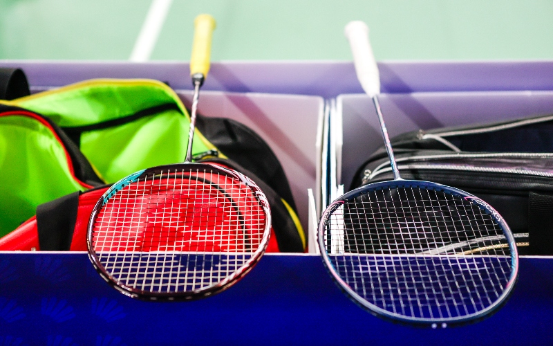 Badminton rackets lying on the kit boxes at the side of a court
